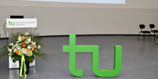 Ein Blumenstrauß rechts unten neben dem großen TU Logo