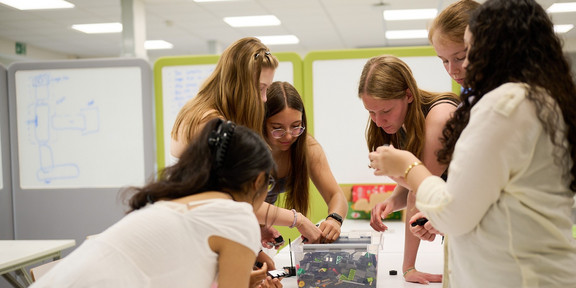 Schoolgirls at the workshop day at the Department of Mechanical Engineering. A group of schoolgirls bend over a box of Lego bricks.
