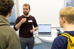 Ein Mitarbeiter der Regelungstechnik erklärt Studierenden ein Versuchsmodell