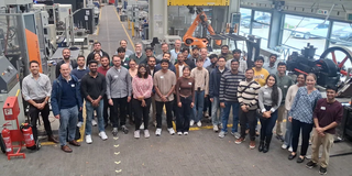 Studierende, Betreuende und Lehrende der MMT-Kohorte 2026 in der Experimentierhalle des IULs. 