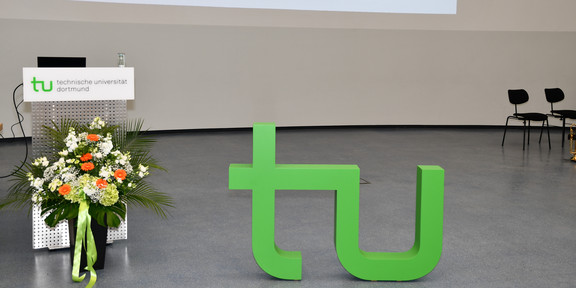 Absolventenfeier 2024 Ein Blumenstrauß rechts unten neben dem großen TU Logo