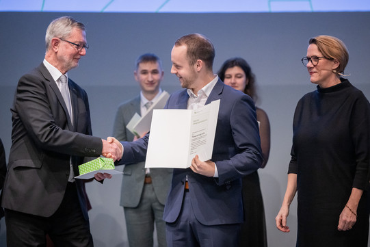 The chairman of the Society of Friends of TU Dortmund University, Guido Baranowski, and the vice-rector for academic affairs, Prof. Wiebke Möhring, present the prize for the best student of the year to Tobias Schrage.