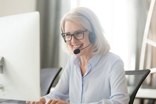 Frau in Videokonferenz Eine Frau sitzt vor ihrem Laptop und trägt ein Headset.