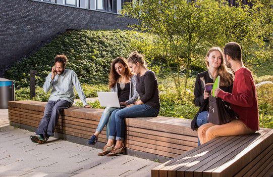 Students sitting on a seating area behind the new physics building.