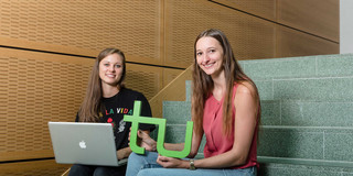 Studentinnen mit Laptop und TU-Logo Zwei Studentinnen sitzen mit Laptop und TU-Logo auf einer Treppe.