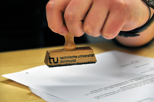 close-up of a hand holding a stamp over a piece of paper