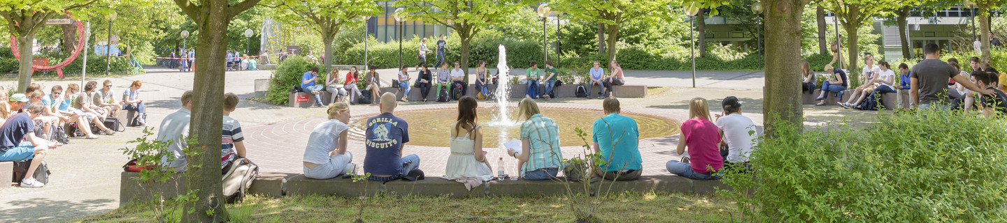 Studenten sitzen im Sommer am Brunnen des Martin-Schmeißer-Platzes