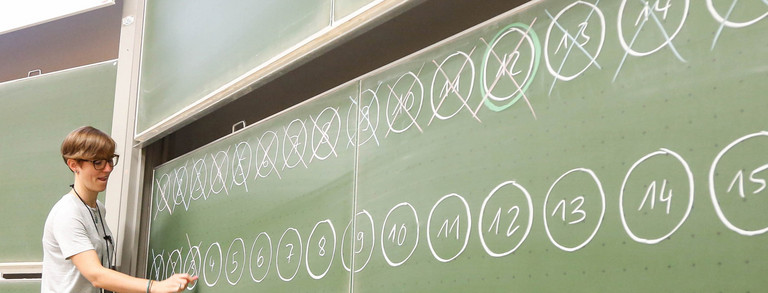 Lecturer and a young boy are standing in front of a blackboard